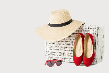Beyaz hasır çanta, kadın şapka, güneş gözlüğü ve kırmızı ayakkabılar.