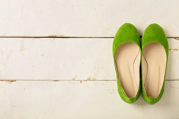 Green women\'s shoes (ballerinas) on wooden background.