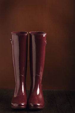 Düşük anahtar fotoğrafta. Üzerinde kahverengi bir backgro bordo renk lastik çizmeler