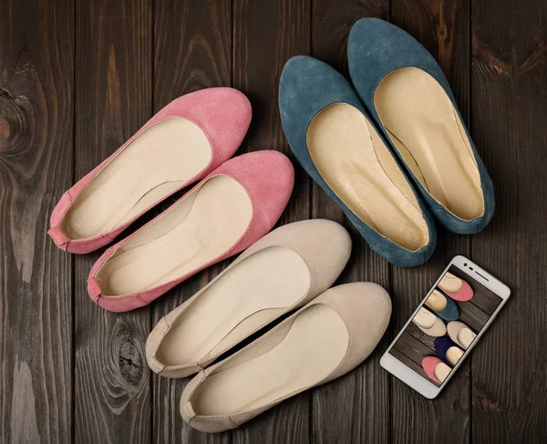 Women's shoes (ballerinas) pink, blue and beige on a dark wooden