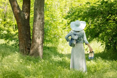 Genç kadın şapka ve uzun bir etek bir parkta yürüyen bir 
