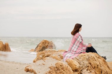 Genç kadın ile kaplıdır halı üstünde belgili tanımlık deniz kıyısı ve içki oturur