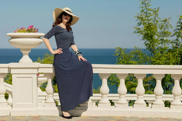 Young woman in a long dark blue skirt on the waterfront near the