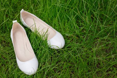 Yeşil çimenlerin üzerinde beyaz kadın ayakkabıları. Bulanık makro fotoğraf. 