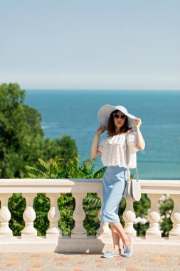 Genç kadın bir beyaz bluz, mavi kalem etek ve şapka bir ba