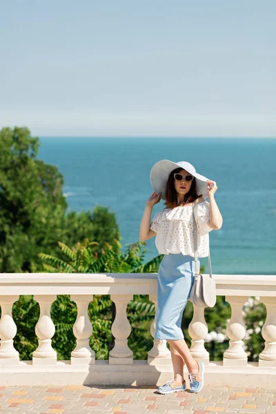 Genç kadın bir beyaz bluz, mavi kalem etek ve şapka bir ba