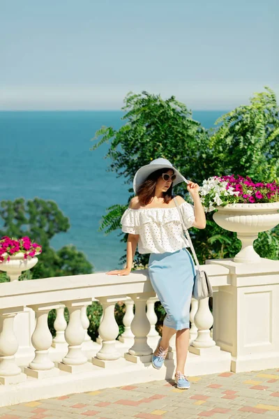 Genç kadın bir beyaz bluz, mavi kalem etek ve şapka bir ba