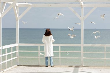 Genç kadın (esmer) Beyaz önlük martılar beslemeleri olmak