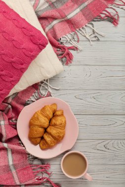 Örgü yastıklar ve ekose, kruvasan ve kahve ışık ahşap üzerine