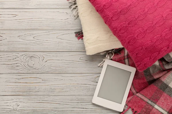 Örgü yastıklar, ekose ve hafif ahşap arka plan üzerinde ebook. 