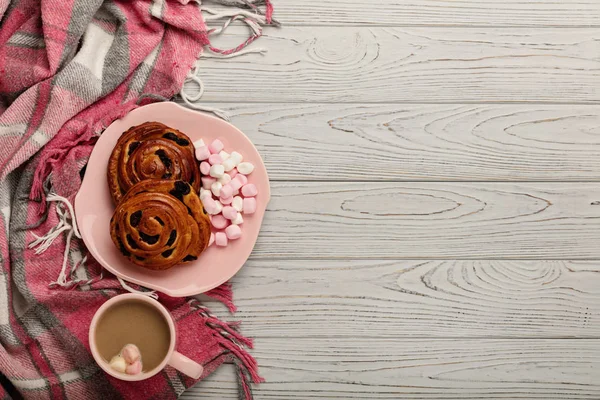 Örgü yastıklar ve ekose, çörek ve kahve bir ışık ahşap bac üzerinde