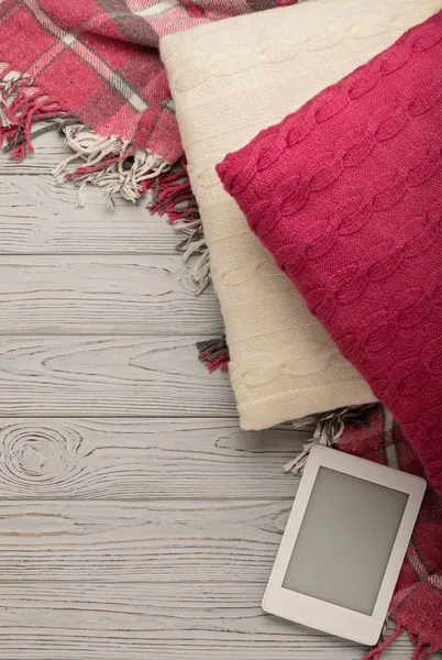 Örgü yastıklar, ekose ve hafif ahşap arka plan üzerinde ebook. 