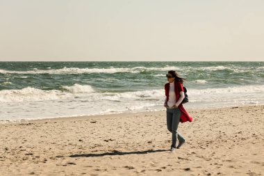 Genç kadın (esmer) kırmızı bir hırka ve ışık mavi jeans, w