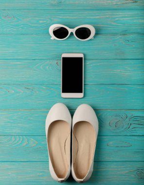Beyaz renk, mavi bir smartphone kadın ayakkabı ve güneş gözlüğü 