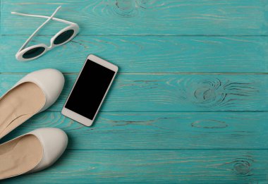 Beyaz renk, mavi bir smartphone kadın ayakkabı ve güneş gözlüğü 