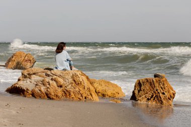 Genç kadın (esmer) bir ışık altında mavi hırka ve kot pantolon, ile 