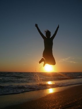 Günbatımında atlama bir adam silüeti