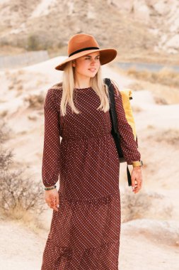 Kum vadisi ve kayalarda yürüyen kahverengi şapkalı ve uzun elbiseli gezgin bir kadın. Seyahat ve seyahat tutkusu konsepti. Kapadokya, Türkiye.