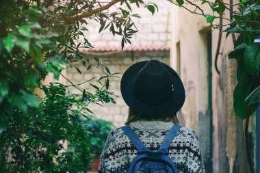 Gezgin kadın daha tatlı, kot pantolon ve şapkalı ve boho tarzı sırt çantalı eski Akdeniz mahallesinde yalnız. Kadın seyahatleri konsepti. 