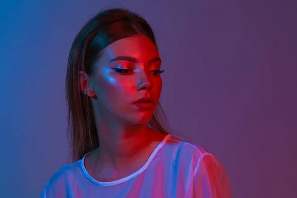 Neon close up portrait of young woman. Studio shot. Model posing in purple, red and pink lights. Fashion back to 80s - 90s new trend concept.