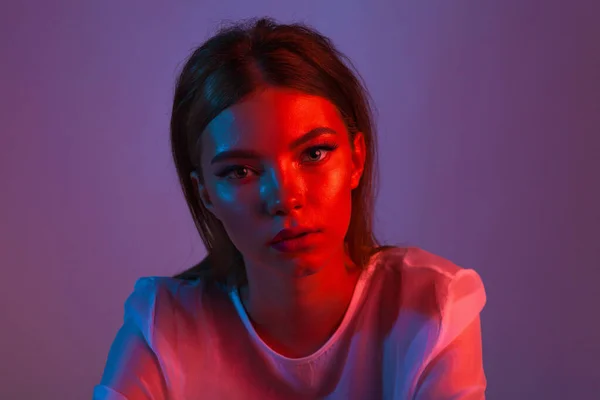 Neon close up portrait of young woman. Studio shot. Model posing in purple, red and pink lights. Fashion back to 80s - 90s new trend concept.