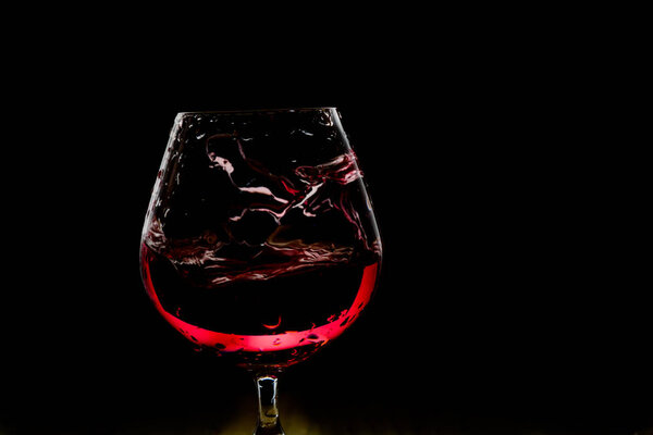 Splash of wine in the glass on dark backround