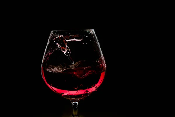 Salpicadura de vino en la copa en el fondo oscuro —  Fotos de Stock