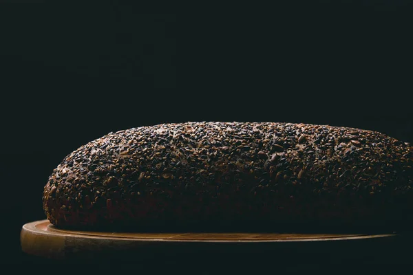 Black bread with seeds on dark background