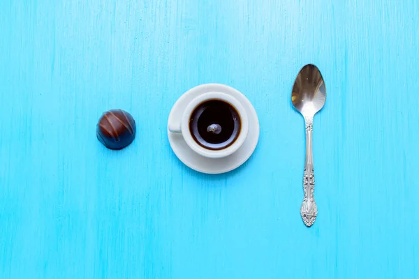 Una pequeña taza de café, dulces y cuchara en la mesa azul — Foto de Stock