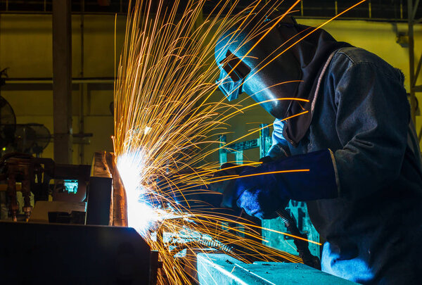 Worker,welding in a car factory with sparks,