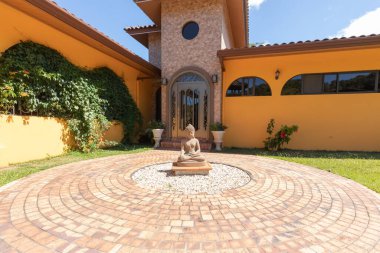 Orosi Costa Rica March 17 buddha statue in front of the main entrance of a luxury colorful residence sited in the hills of Orosi village in Central Costa Rica. Shoot on March 17, 2020 clipart