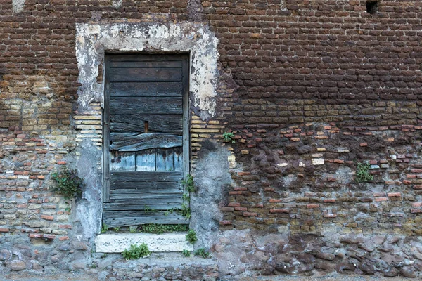 Bir tuğla duvar eski ahşap kapı. Sağ tarafta yer
