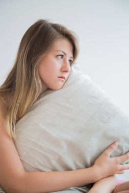 ciddi genç kadın yastığının üzerinde yatak portre kucaklayan