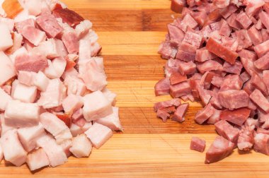 Pastırma ve ahşap kesme tahtası üzerinde küçük küpler halinde İtalyan sosis.