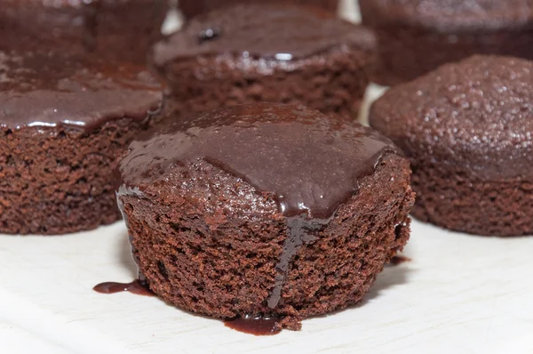 Small chocolate cakes with dripping chocolate icing on top.