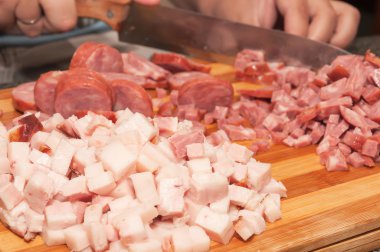 Bir tabak yemek hazırlanması için malzemeler. Pastırma ve İtalyan sosis kesme tahtası üzerinde dilimlenmiş ağaçtan