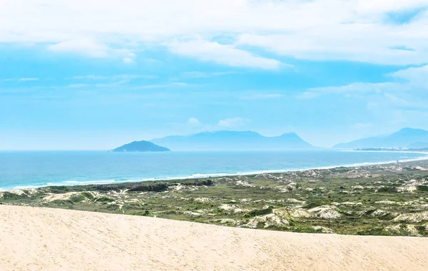 Пляж, песок, зеленая растительность, голубой океан и некоторые горы на заднем плане — стоковое фото