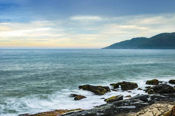 Salida del sol con olas de agua salpicando sobre rocas marinas —  Fotos de Stock