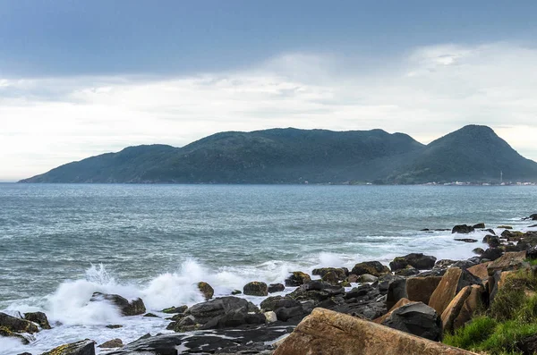 Ondas do mar de água salpicando em rochas do mar na costa do mar e uma montanha — Fotografia de Stock
