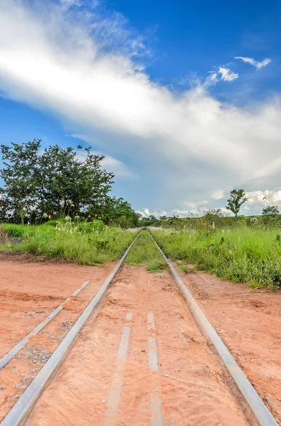 Train track passing by the dirt road going to the grass — Stock Photo, Image