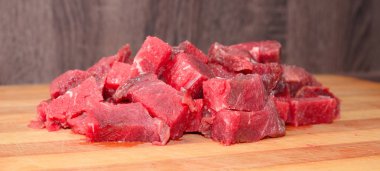 Kırmızı et kısmı bir ahşap tahta küpler halinde dilimlenmiş