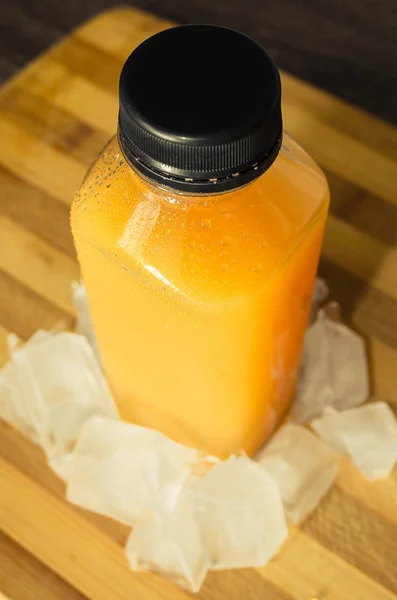 Sebotol jus jeruk dengan beberapa es di sekitar — Stok Foto