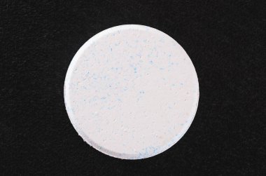 White rounded chlorine tablet isolated on a dark textured backgr clipart
