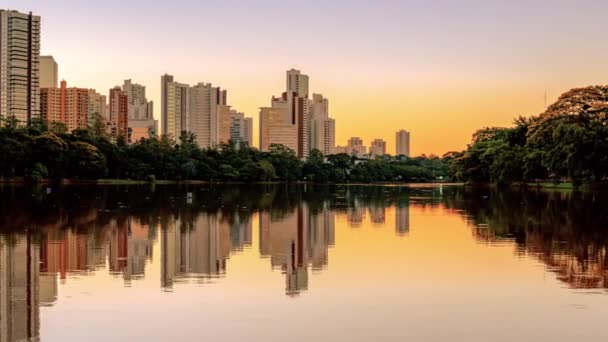 美しい夕日の街の湖の眺め 木々の緑の領域と湖の海岸 背景に街のいくつかの建物 側スクロールビデオのIgapo湖にロンドリーナPrブラジル — ストック動画