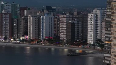 Yüksek binaları ve gece plajı olan bir sahil şehri manzarası. Geceleri Sao Vicente şehri, Sp Brazil. 