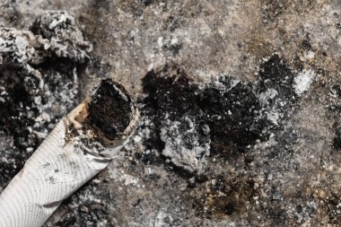 Smoked cigarette on the ashtray with ashes around. Cigarette butt and ashes.
