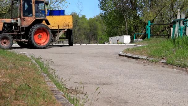 Traktorn är i rörelse längs gränden — Stockvideo