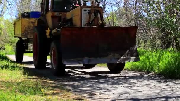 Traktorn är i rörelse längs gränden — Stockvideo