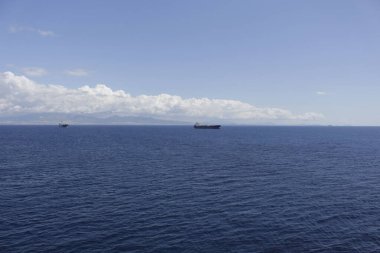 Bir deniz gemisi adaların arka planına ve mavi gökyüzüne karşı uzaklaşıyor..