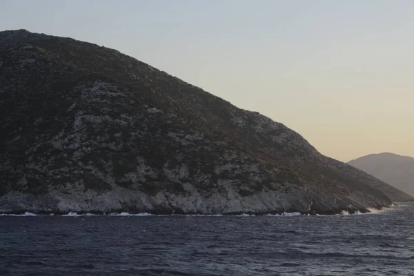 Adanın tepeleri Akdeniz 'in karanlık sularına batar. Uzakta, sisin içinde dağın zirvesini görebilirsiniz..
